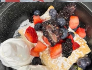 Fried pastry dessert topped with berries and whipped cream